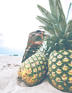 two pineapples on sand during daytime thumbnail