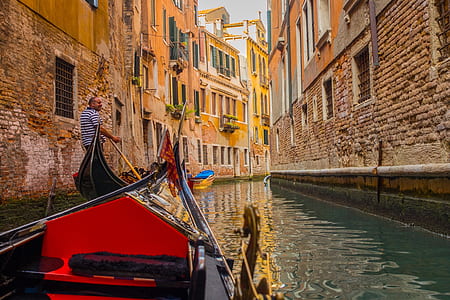 person riding boat on canal near buildings thumbnail