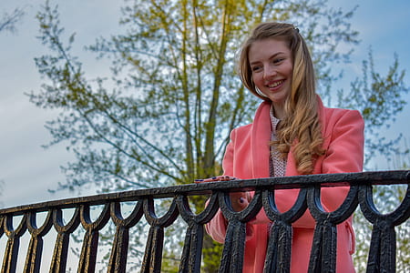 smiling woman standing beside gray metal fence at daytime thumbnail