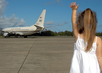 girl in white spaghetti strap dress waving at white passenger airplane thumbnail