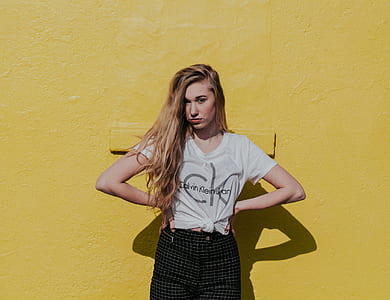 woman standing near yellow concrete wall during daytime thumbnail