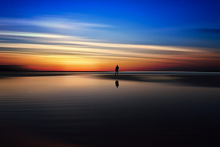 silhouette of man near body of water during sunset thumbnail