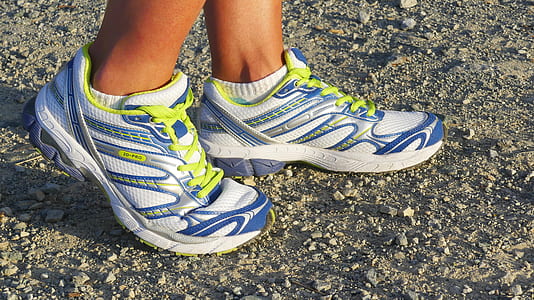 person wearing pair of white-yellow-and-red running shoes while standing on ground at daytime thumbnail