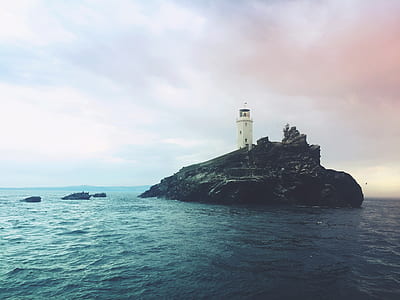 white lighthouse surrounded by body of water thumbnail