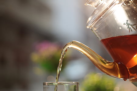 clear glass teapot pouring tea on clear drinking glass thumbnail