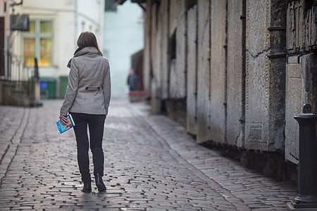 woman holding blue covered book walking in street thumbnail