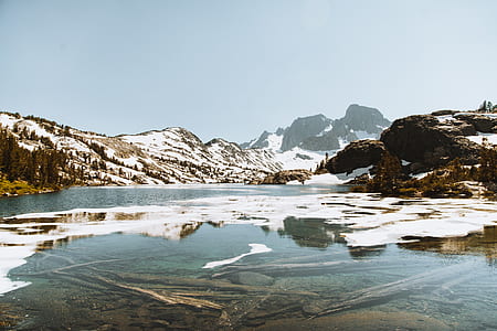snow covered mountains overlooking body of water thumbnail