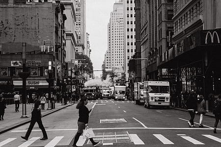 grayscale photography of woman carrying paper bag while crossing the pedestrian lane thumbnail