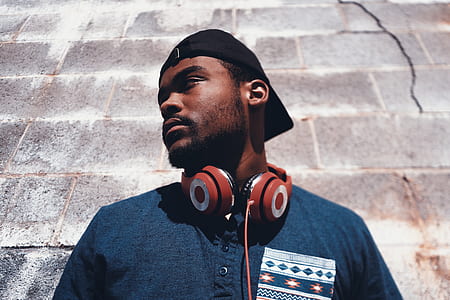 man in blue henley shirt wearing red headphones in front of brown brick wall thumbnail