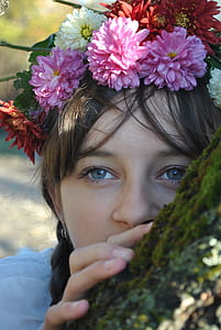 girl with floral headband touching tree trunk thumbnail