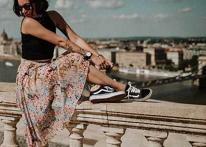 shallow focus photography of woman sitting on concrete fence thumbnail