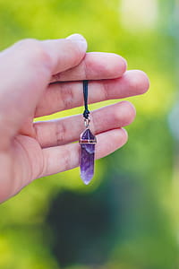 Person Holding Purple Gemstone Pendant thumbnail