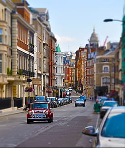 red vehicle traveling on road between buildings at daytime thumbnail