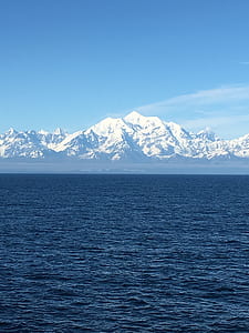 long-angle photography of snow-coated mountain and sea under blue calm sky thumbnail