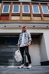 man in blue denim jacket near brown and white building thumbnail