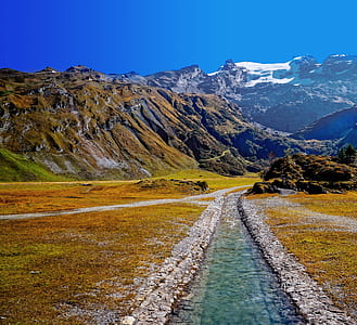green grass field, mountains and river photo during daytime thumbnail