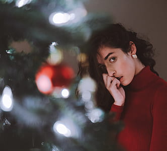 woman standing behind of Christmas tree while taking selfie picture thumbnail