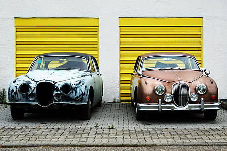 two brown and gray car parked beside white and yellow building thumbnail
