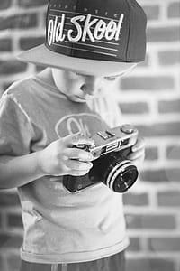 grayscale photo of boy holding rangefinder camera thumbnail