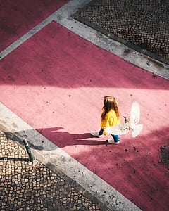 high angle photography of white bird flying above woman walking on red floor thumbnail