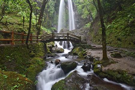 time lapse photography of water flowing on the rocks with bridge thumbnail