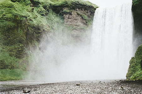 waterfalls surrounded by mossy rock formation during daytime thumbnail