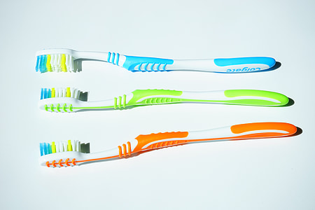 three blue, green, and orange Colgate toothbrushes thumbnail