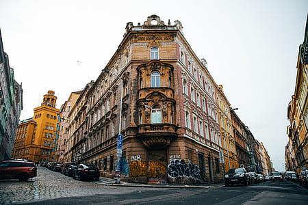 An old corner building in Prague with cars parked on the streets along both sides thumbnail
