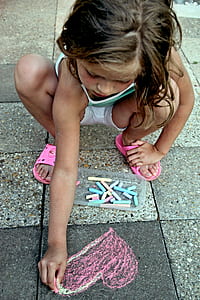 girl drawing heart on pavement thumbnail