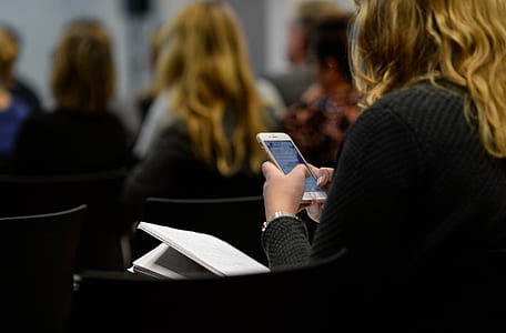 woman wearing black sweater sitting inside the room while using smartphone thumbnail