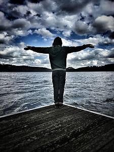 person in black jacket and black pants standing on dock thumbnail