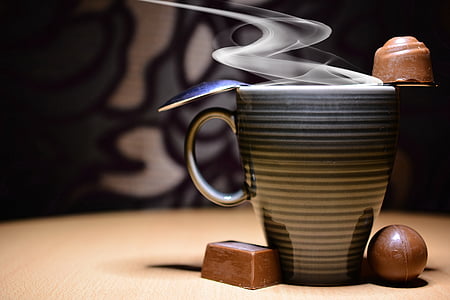 gray and black striped ceramic coffee mug between two chocolates thumbnail