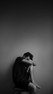 grayscale photograph of man sitting down chair thumbnail