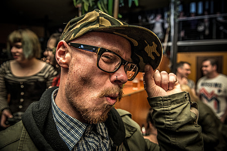 man in green zip-up hoodie holding hat while smiling thumbnail