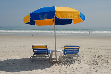 blue-and-yellow lounger chairs with umbrella on the beach during daytime thumbnail