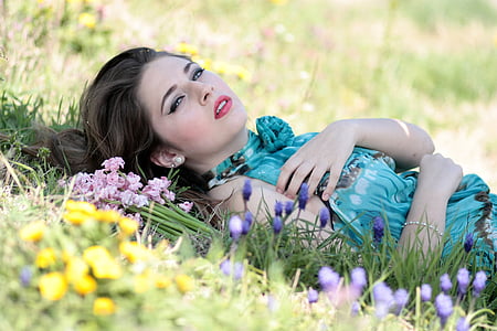 woman lying on flowerfield beside pile of pink clustered petal flowers thumbnail