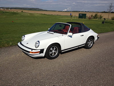 classic white convertible coupe parked on asphalt road beside green grass open field during daytime thumbnail