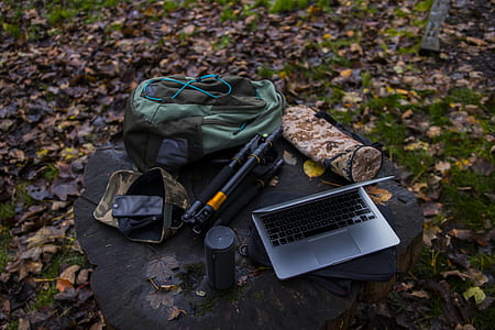 silver laptop near black portable speaker, tripod, and backpack on stone thumbnail