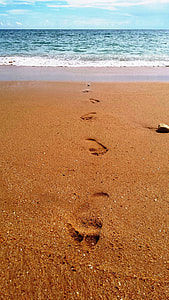 human foot prints on sand near seashore during daytime thumbnail