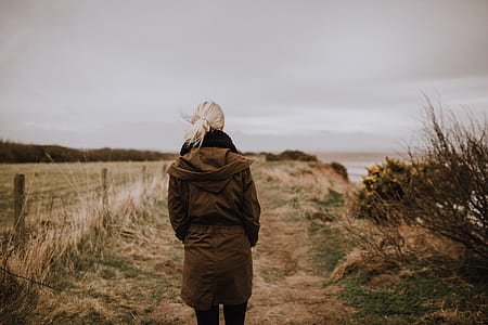 woman standing in the middle of the field near calm body of water thumbnail