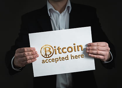man holding Bitcoin accepted here signage thumbnail