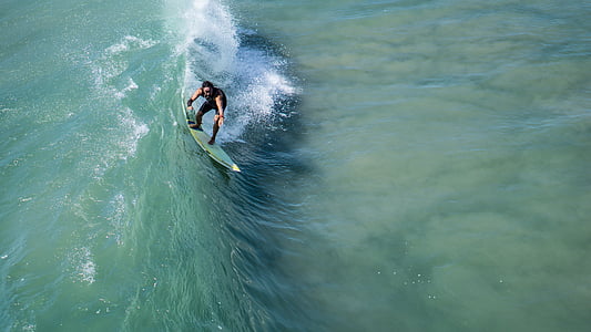 aerial photography of man surfing ocean wave during daytime thumbnail