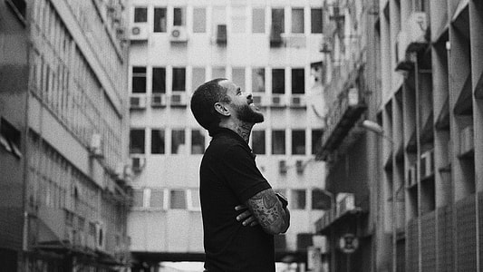 man standing near high rise buildings thumbnail