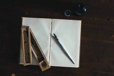 flat lay photography of wooden case and pen on top of open book thumbnail