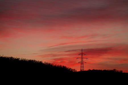 silhouette of elevated terrain with gray metal electric tower during golden hour thumbnail