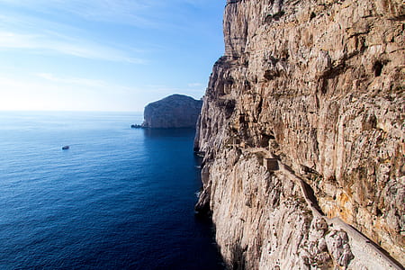 body of water near mountain under blue sky at daytime thumbnail