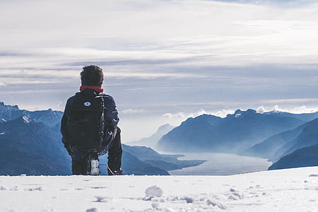 man sitting on snow covered mountain peak thumbnail
