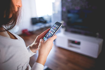 shallow focus photography of woman in v-neck long-sleeved top holding space gray iPhone 6 thumbnail