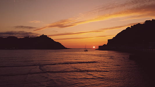 boat on ocean under orange sunset thumbnail