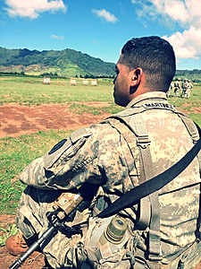 man sitting on ground holding black rifle thumbnail